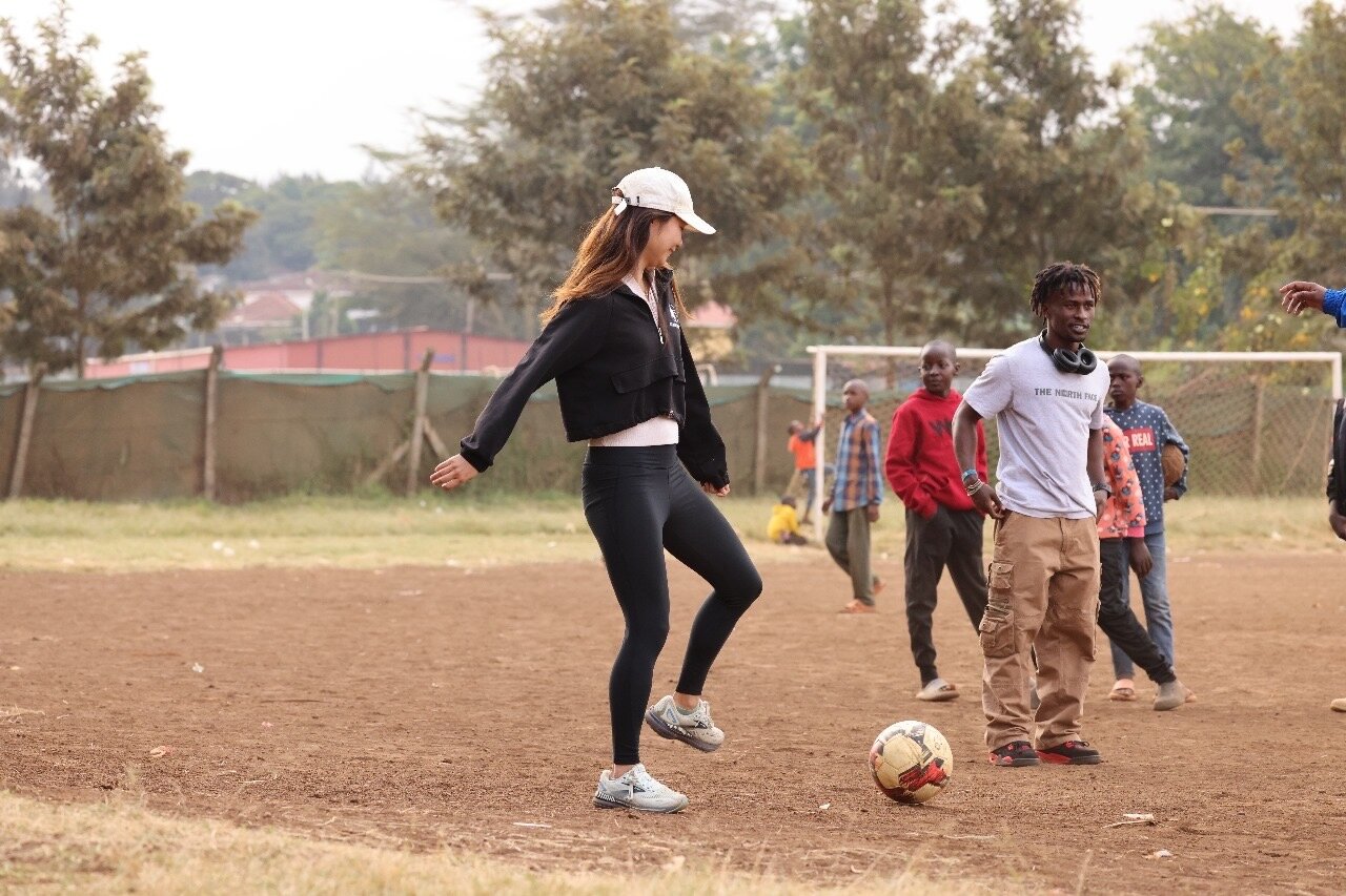 Karis playing soccer on a Kenyan dirt field with TAFA youth and staff
